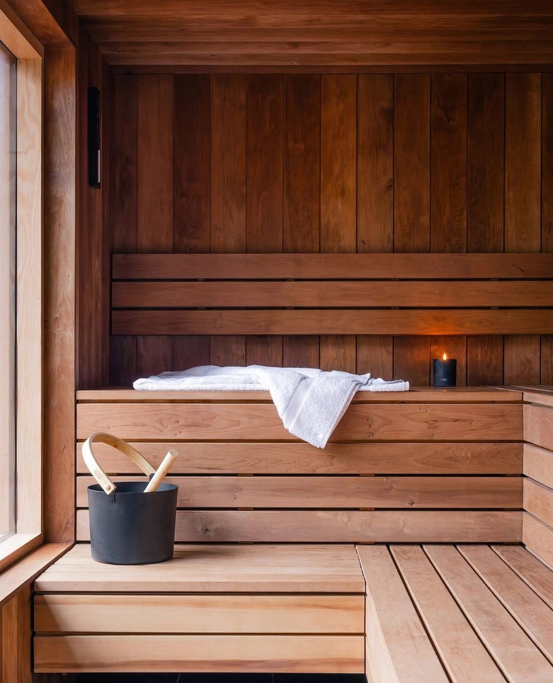 Leere Holzsauna mit Tuch, Kübel und Kerze