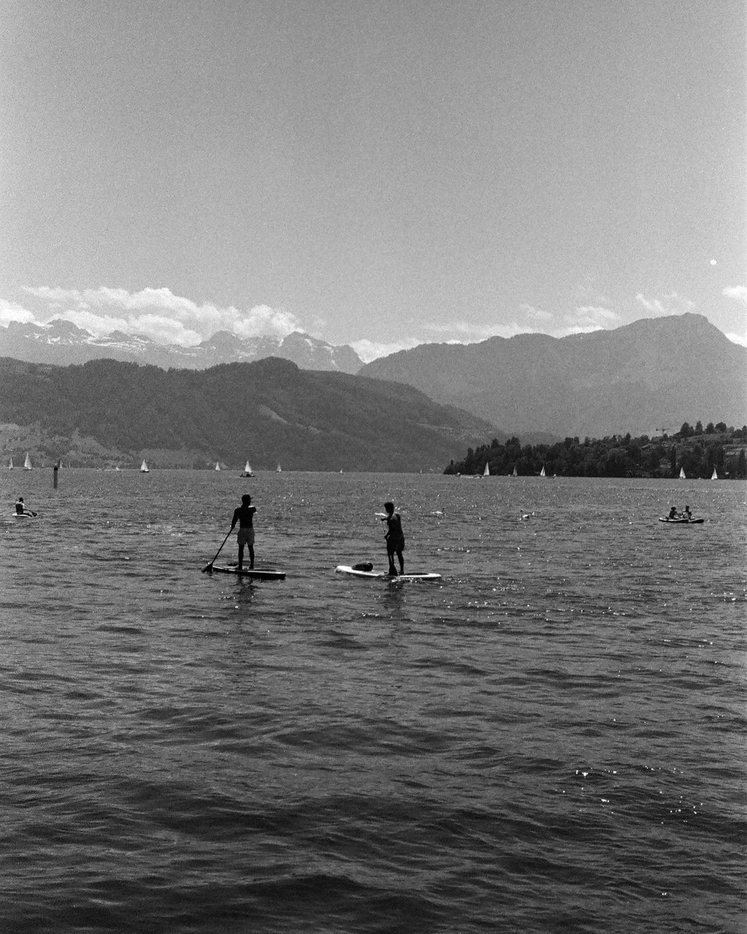 Person auf einem Stand-up-Paddle auf dem See, schwarz-weiss